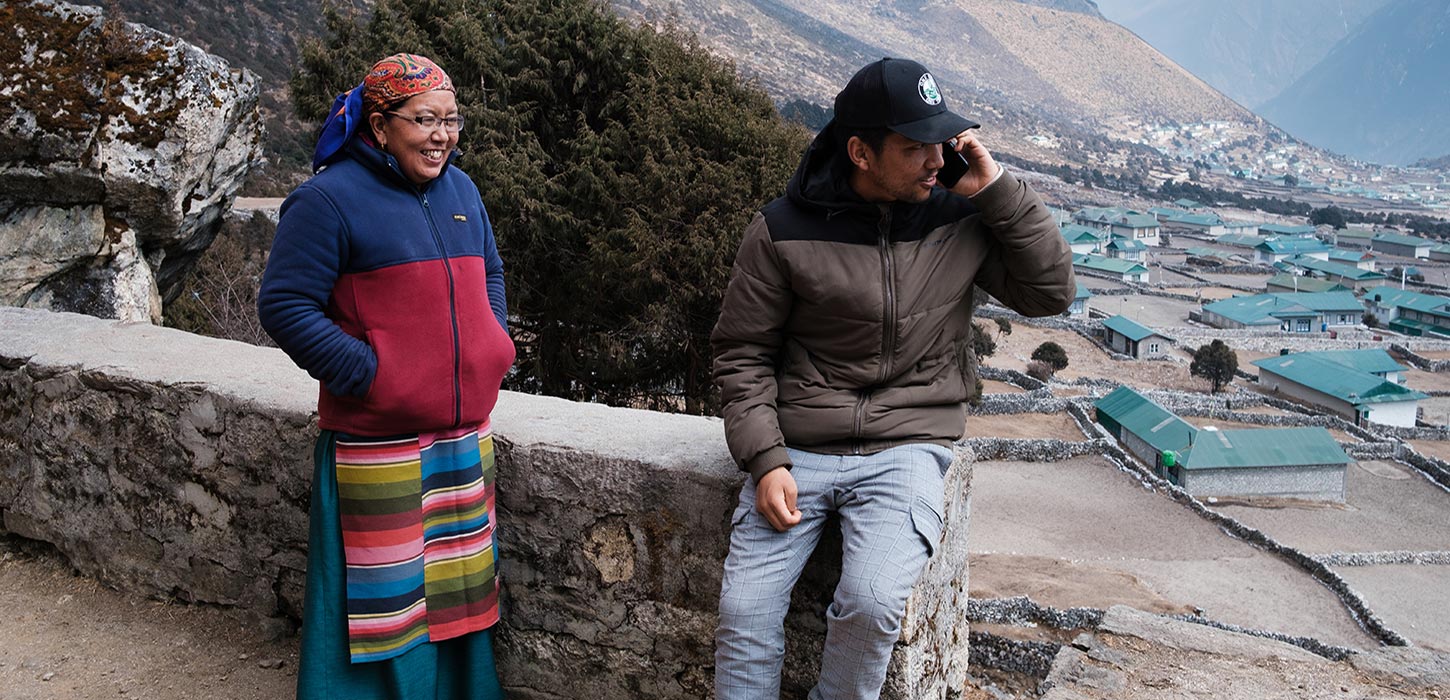 A man talking on the phone and a woman standing next to him and smiling
